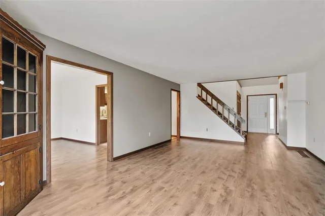 a view of an empty room with wooden floor and stairs