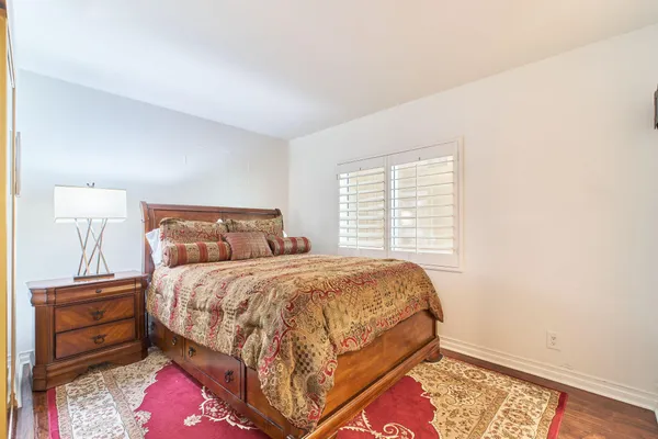 a bedroom with a bed a large window with table and chair