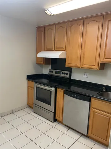 a kitchen with granite countertop a stove a sink and dishwasher