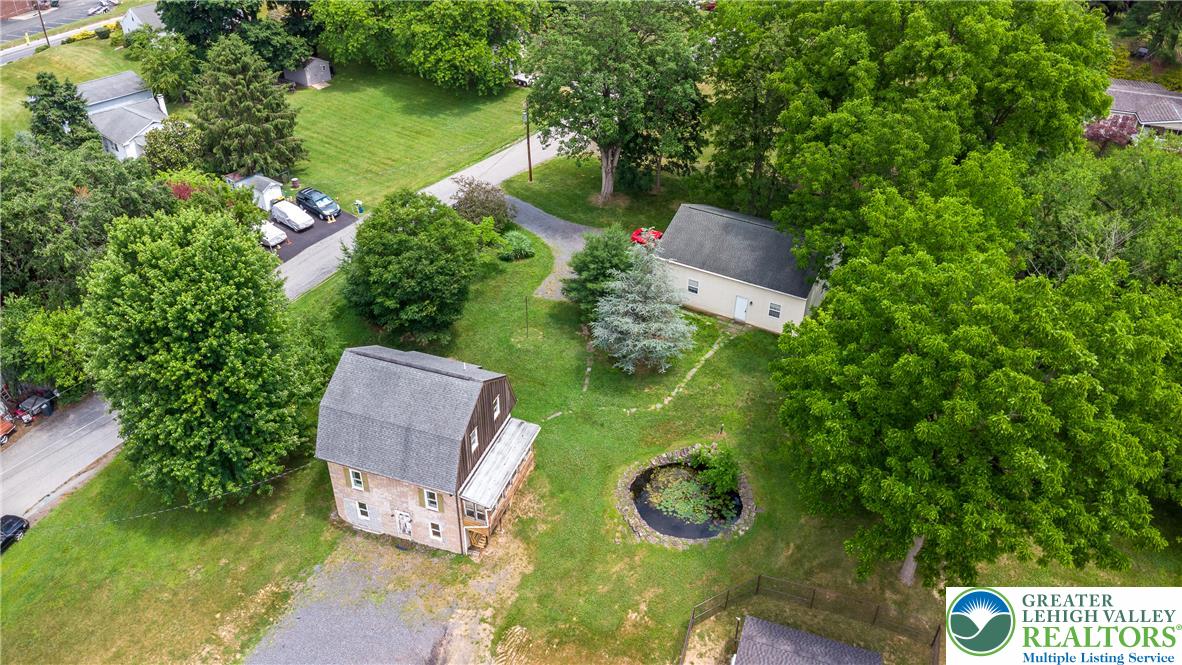 An aerial perspective reveals a private pond and multiple structures nestled amidst lush, mature greenery.