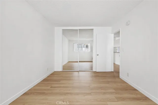 a view of an empty room with wooden floor and closet