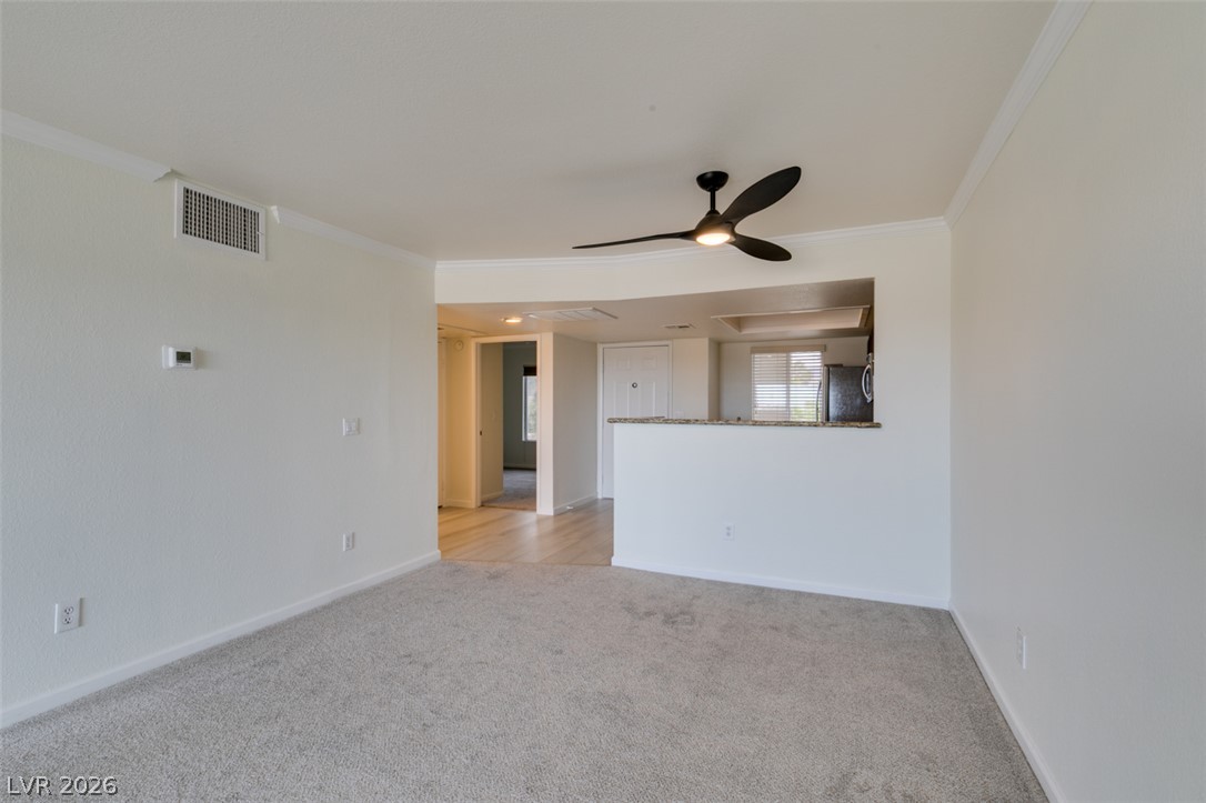 8070 West Russell Road, Unit 2026 Las Vegas, NV 89113 - Photo 10 of 41 A versatile open-concept living space features light carpeting and a stylish ceiling fan.