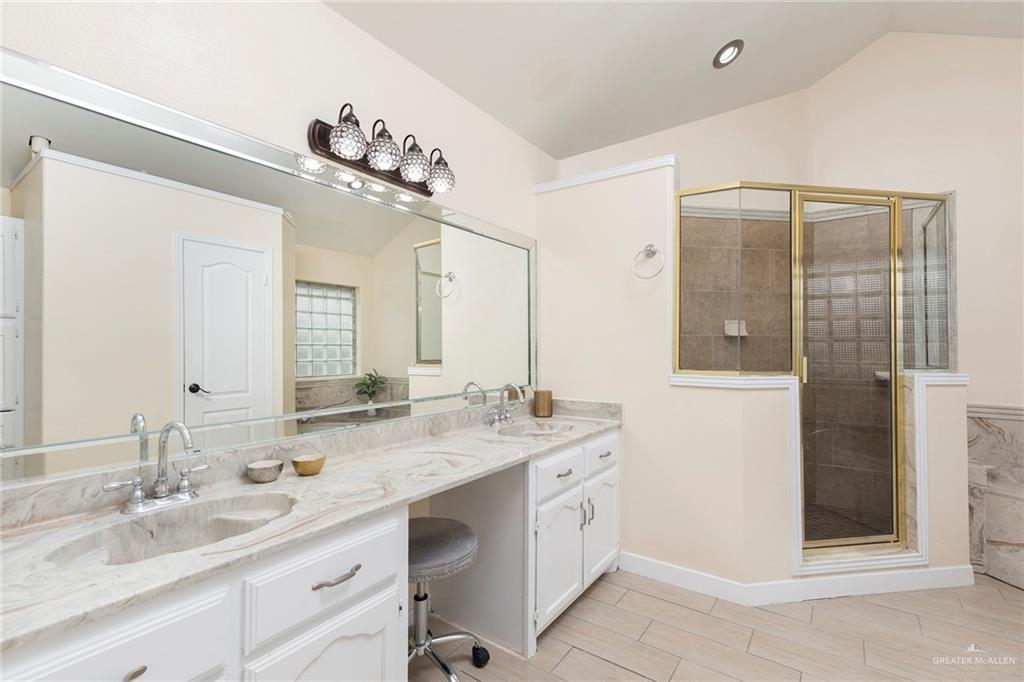 2001 Quail Lane Mission, TX 78572 - Photo 14 of 28 Vanity area featuring dual integrated sinks within a stone-finish countertop, white cabinetry with silver-tone hardware, and an expansive wall-mounted mirror