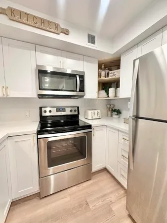 a kitchen with cabinets stainless steel appliances and wooden floor