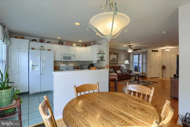 a kitchen with stainless steel appliances kitchen island granite countertop a refrigerator a stove a sink dishwasher a dining table and chairs with wooden floor