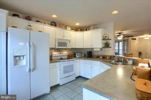 a kitchen with stainless steel appliances granite countertop a refrigerator a sink dishwasher a oven with white cabinets and countertops