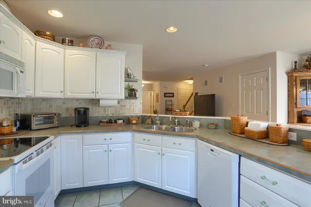 a kitchen with granite countertop white cabinets and white appliances