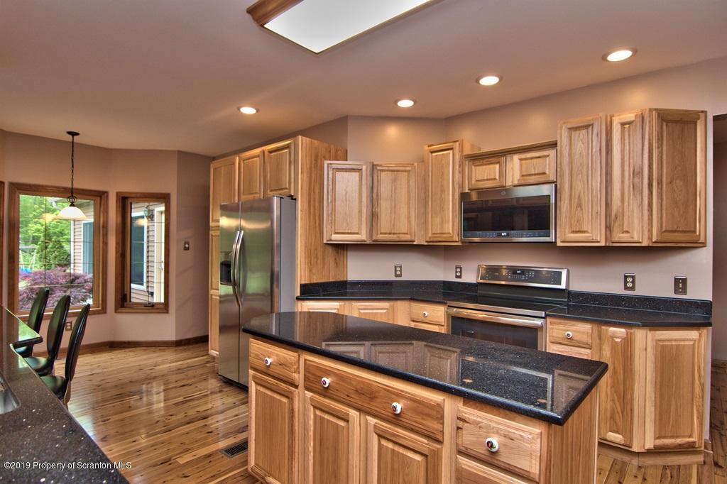 16 Pine Ridge Road Tunkhannock, PA 18657 - Photo 22 of 86 a kitchen with stainless steel appliances granite countertop a refrigerator a stove a sink dishwasher and a microwave with wooden cabinets