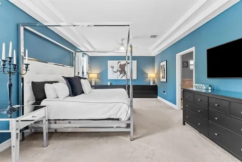 a bedroom with a large bed and a flat tv screen on dresser