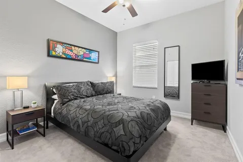 a spacious bedroom with a bed and a flat screen tv