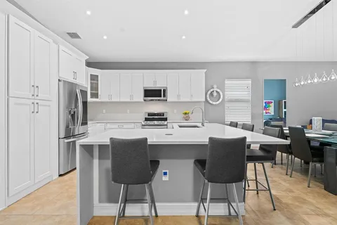 a kitchen with stainless steel appliances kitchen island a table chairs in it and white cabinets