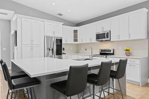 a kitchen with stainless steel appliances granite countertop a stove a refrigerator a microwave sink and white cabinets