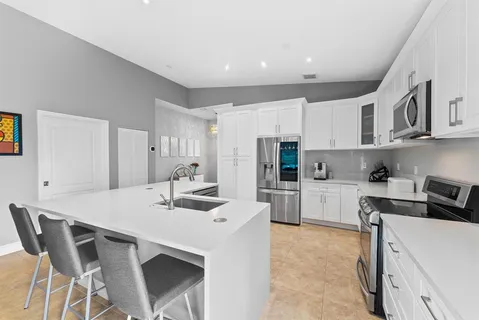 a kitchen with stainless steel appliances a white table chairs and a refrigerator
