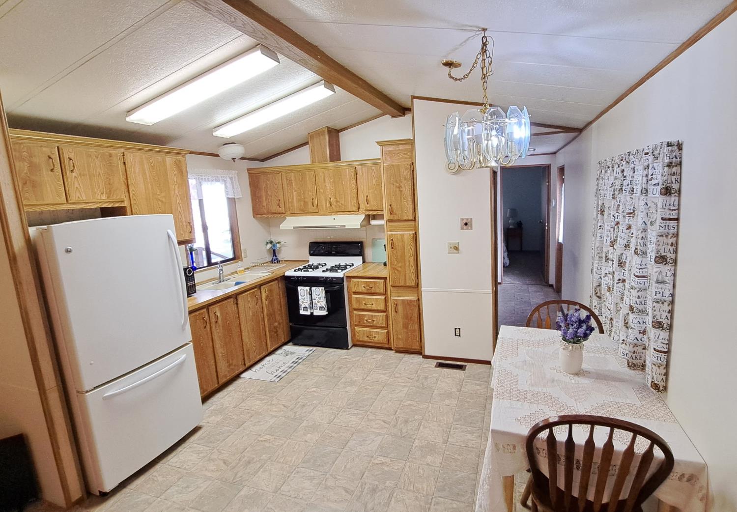 5766 Pony Express Trail, Unit 4 Pollock Pines, CA 95726 - Photo 8 of 17 a kitchen with refrigerator a stove a sink cabinets and a dining table