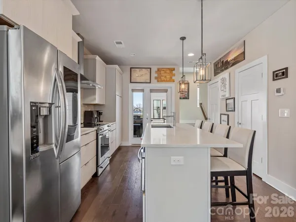 a large kitchen with stainless steel appliances refrigerator a stove and white cabinets