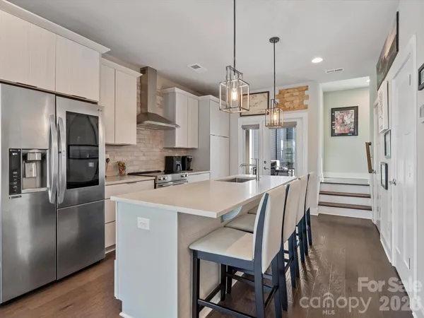 a kitchen with stainless steel appliances a dining table chairs refrigerator and microwave