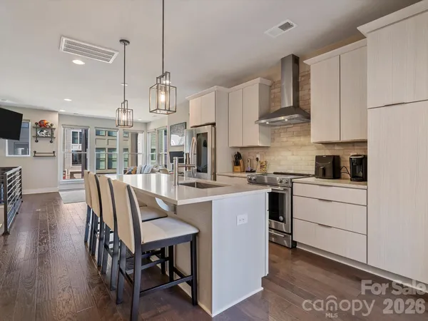 a kitchen with stainless steel appliances granite countertop a stove a sink dishwasher a refrigerator white cabinets with wooden floor