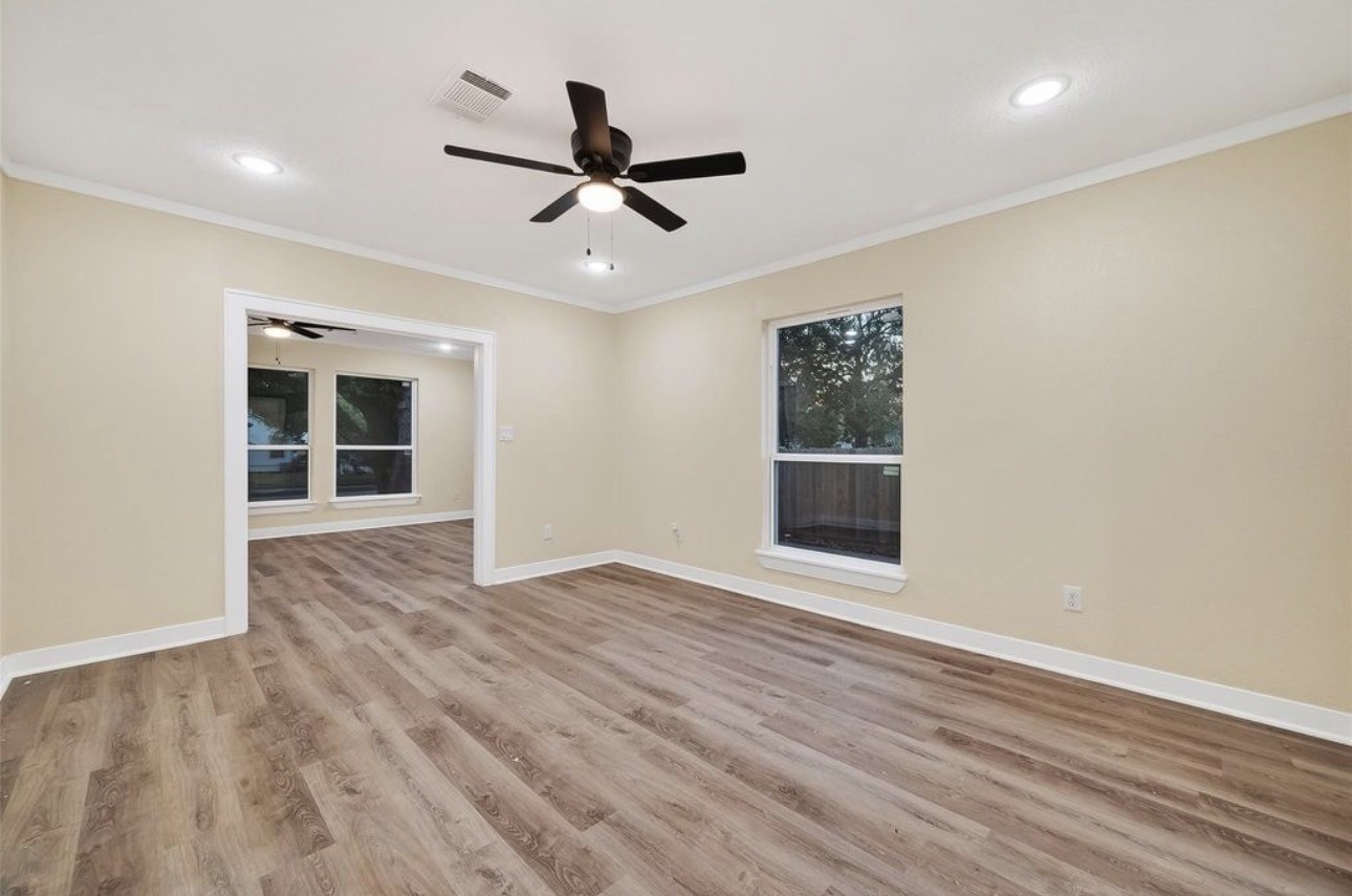 2725 Avenue F Rosenberg, TX 77471 - Photo 5 of 17 an empty room with wooden floor a ceiling fan and windows