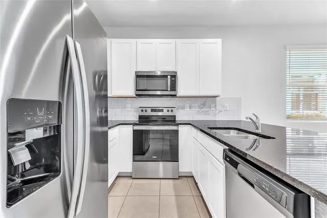 a kitchen with granite countertop a sink stove and refrigerator