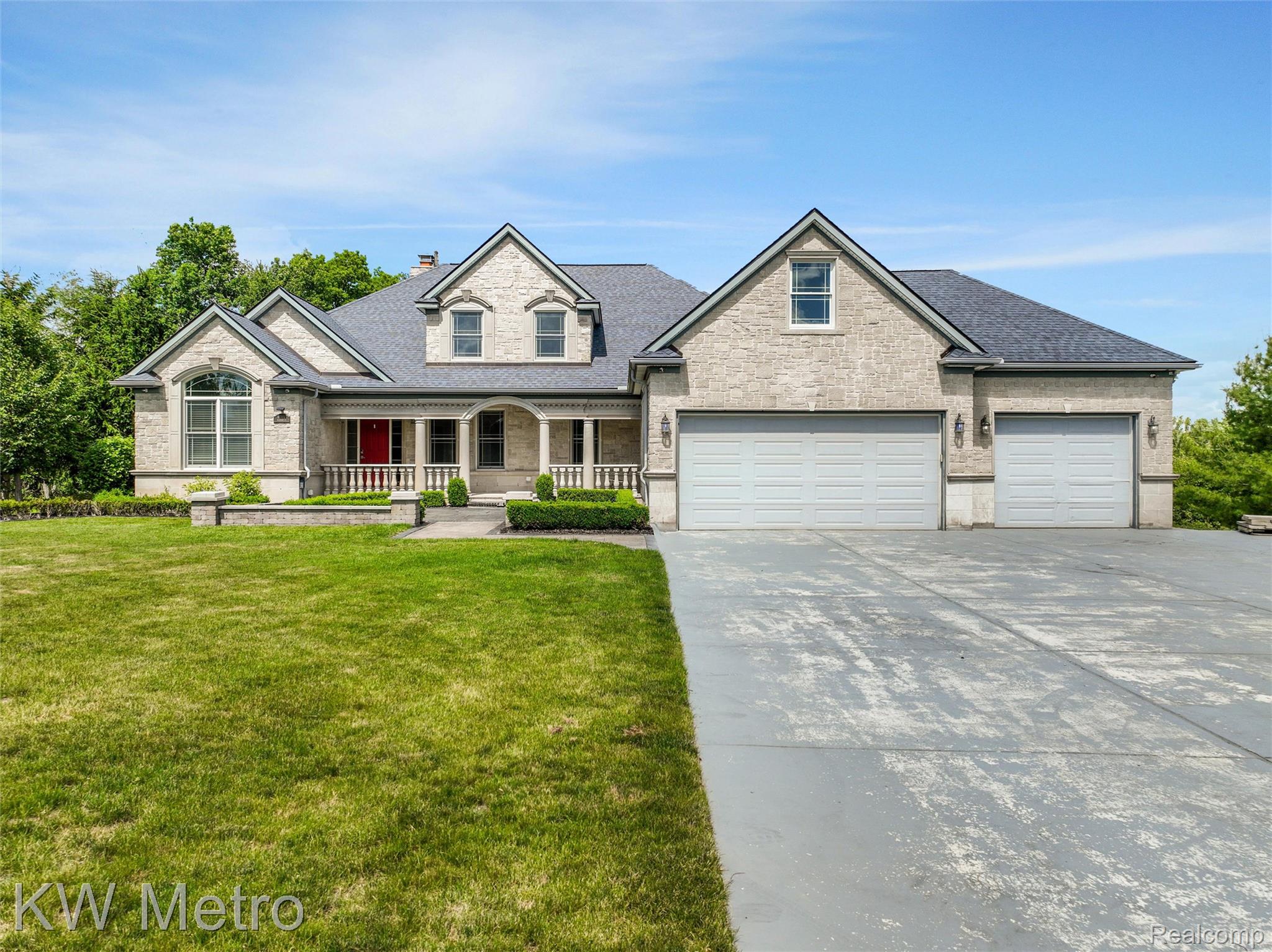 65884 Windrose Court Ray, MI 48096 - Photo 5 of 82 Stone facade residence featuring a covered front porch, arched window details, multiple gables, and a three-car garage