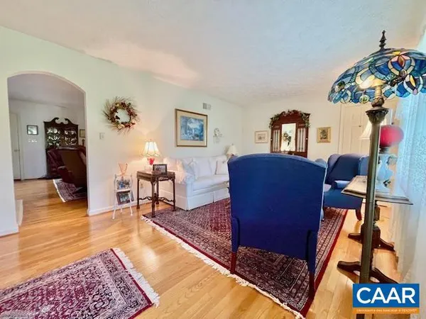 a view of a dining room and livingroom with furniture wooden floor a rug a chandelier and a mirror