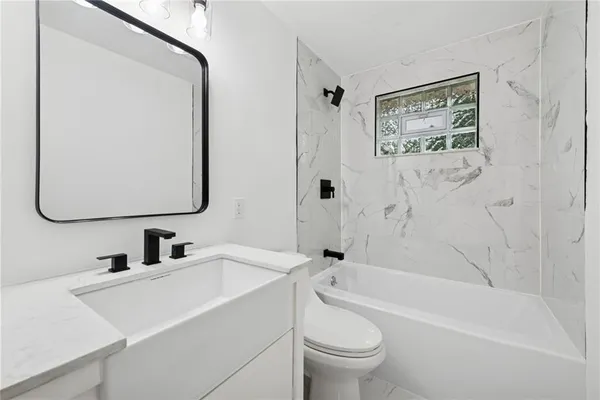 a bathroom with a toilet a sink a mirror and a bathtub