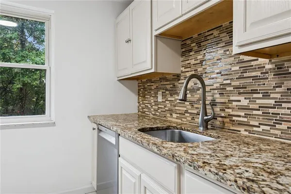 a kitchen with a granite countertop sink a stove and a window