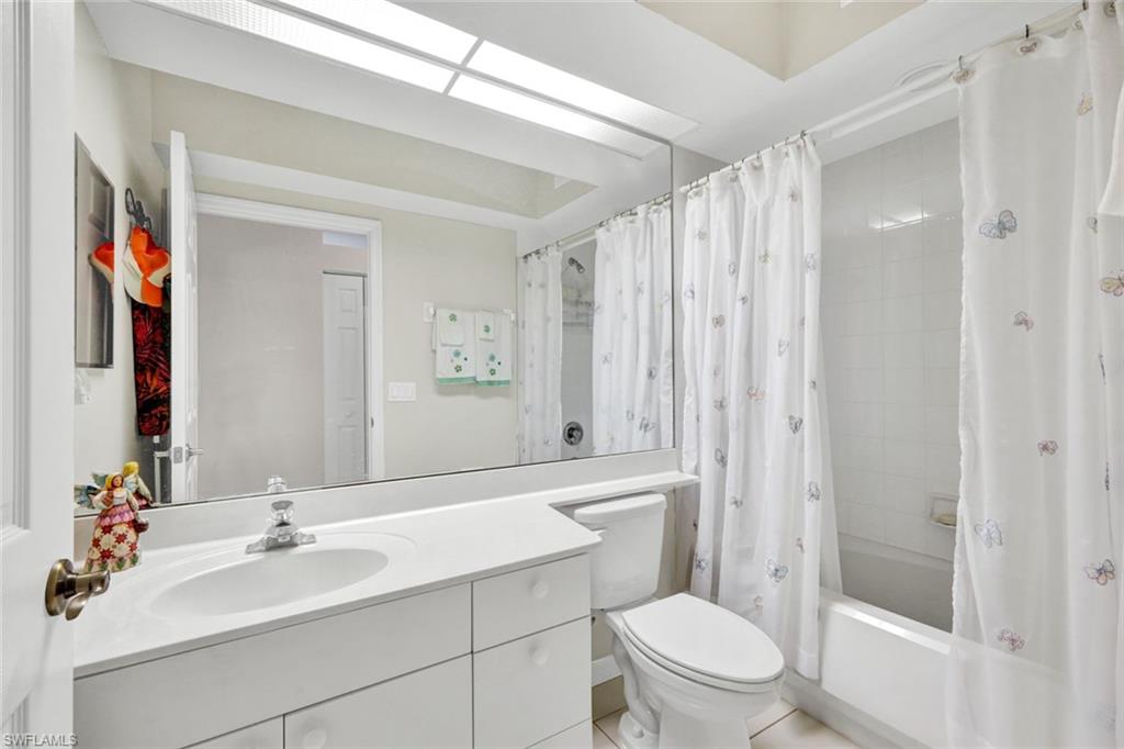 23731 Old Port Road, Unit 103 Estero, FL 34135 - Photo 14 of 30 a bathroom with a sink a toilet and shower curtain