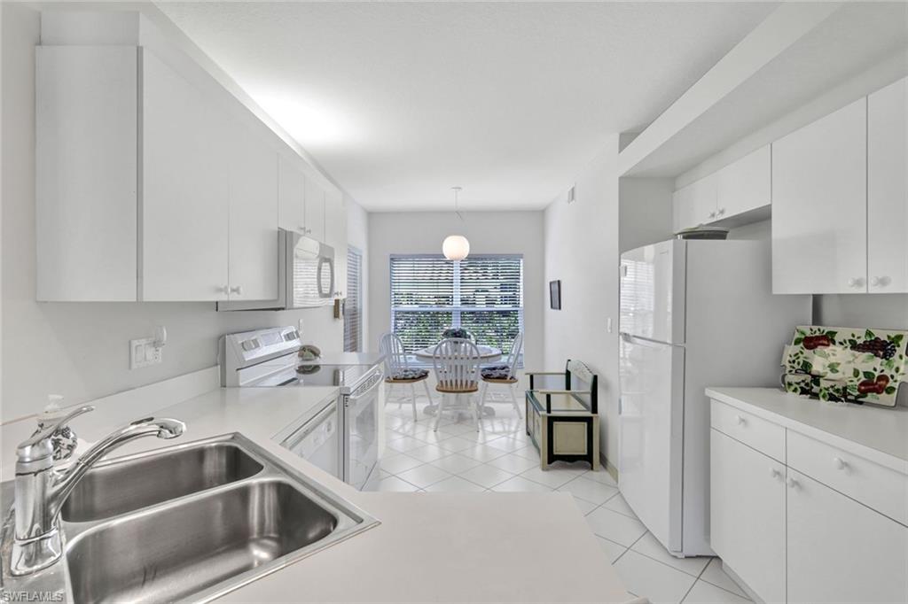 23731 Old Port Road, Unit 103 Estero, FL 34135 - Photo 7 of 30 a kitchen that has a lot of white cabinets and stainless steel appliances