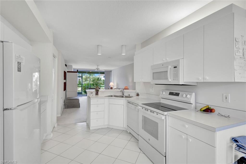 23731 Old Port Road, Unit 103 Estero, FL 34135 - Photo 8 of 30 a kitchen with white cabinets and white appliances