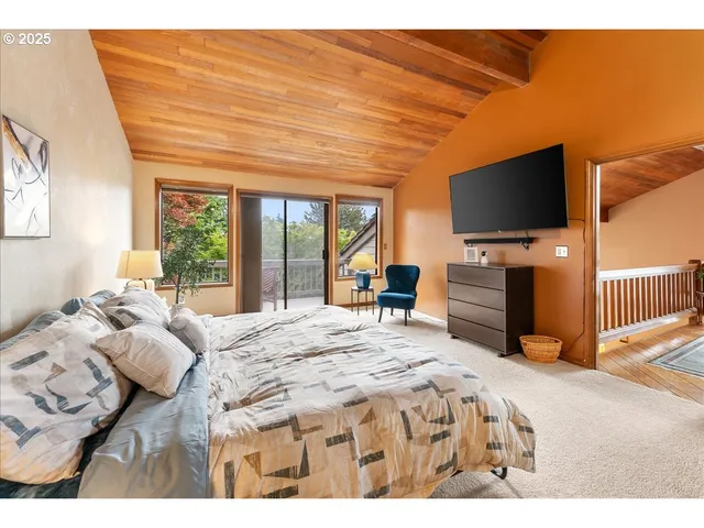 a bedroom with a bed and a flat tv screen on dresser