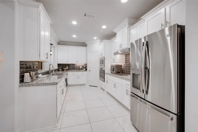 a large white kitchen with granite countertop a sink and cabinets