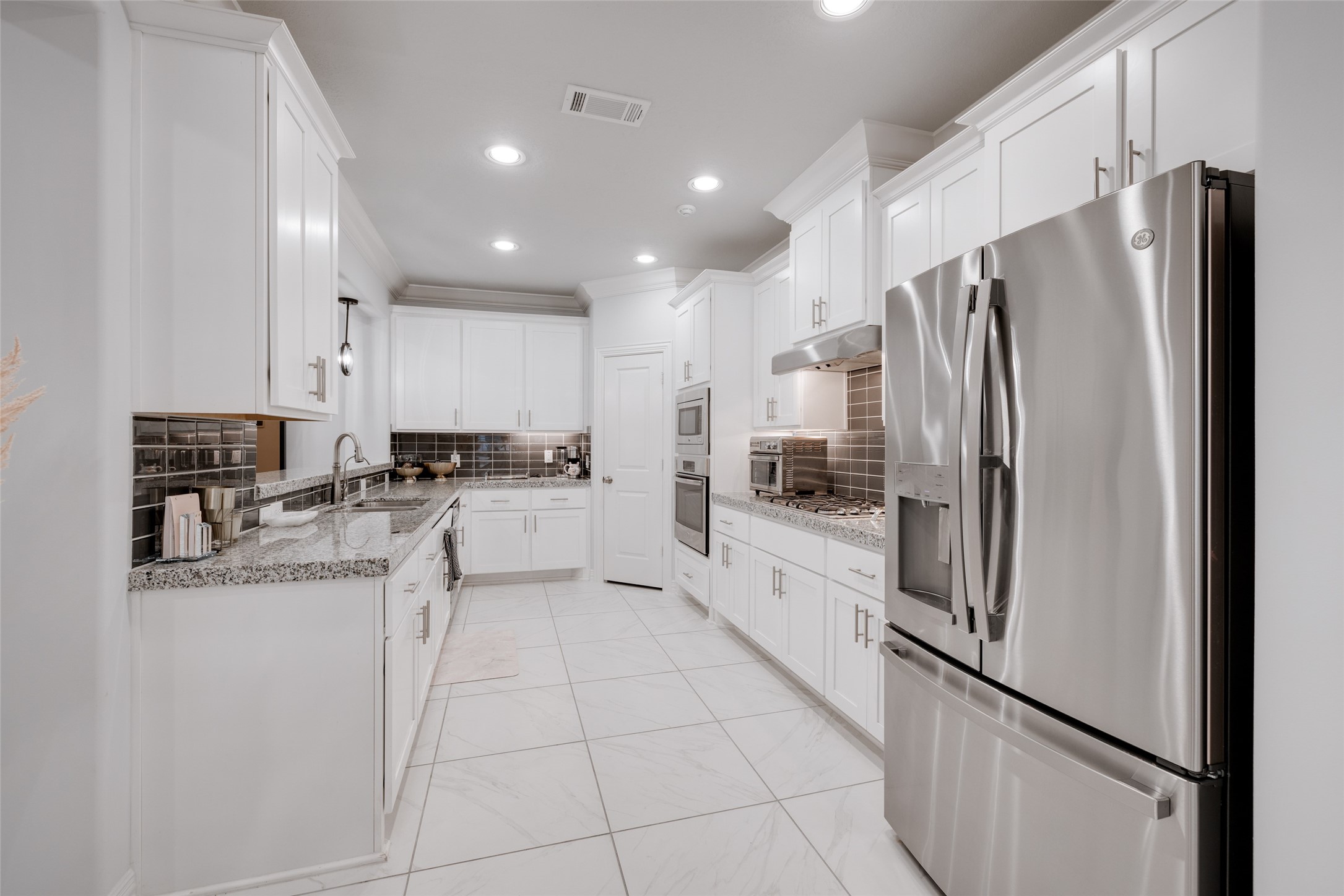 13611 Teal Bluff Lane Houston, TX 77077 - Photo 19 of 46 a large kitchen with a refrigerator a sink and cabinets