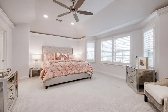 a spacious bedroom with a bed a couch and ceiling fan