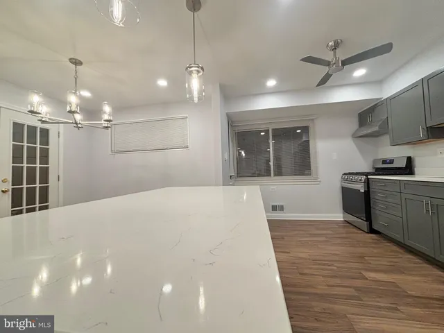 a large white kitchen with a large window a oven and stainless steel appliances