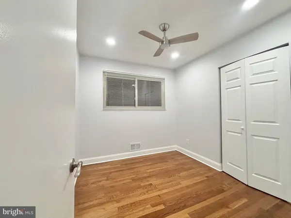 a view of empty room with wooden floor and fan