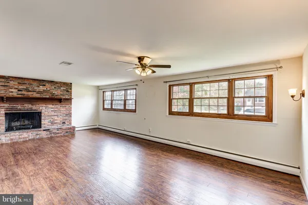 an empty room with wooden floor fireplace and windows