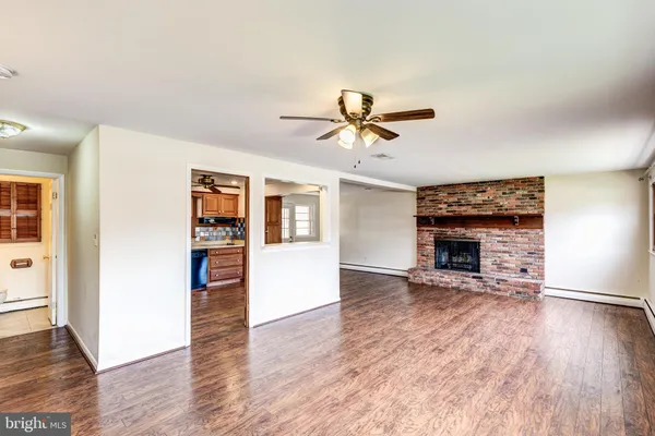 an empty room with wooden floor a ceiling fan and a kitchen