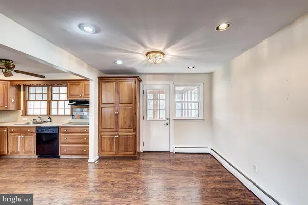an empty room with wooden floor and a kitchen