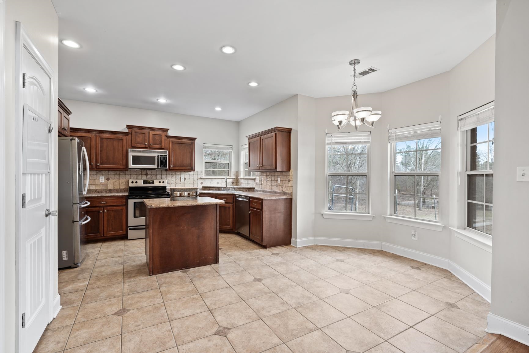 8169 Miller Road Atoka, TN 38004 - Photo 22 of 40 a large kitchen with kitchen island granite countertop a large counter top stainless steel appliances a window and cabinets