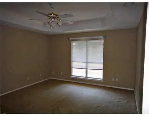 an empty room with a ceiling fan and window