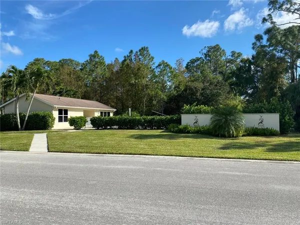 a view of a house with a big yard and large trees