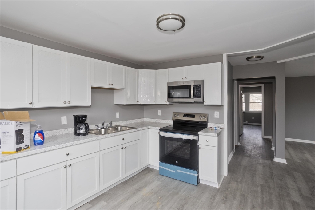 44 Eagle Street Springfield, MA 01107 - Photo 15 of 38 a kitchen with cabinets stainless steel appliances a sink and wooden floor