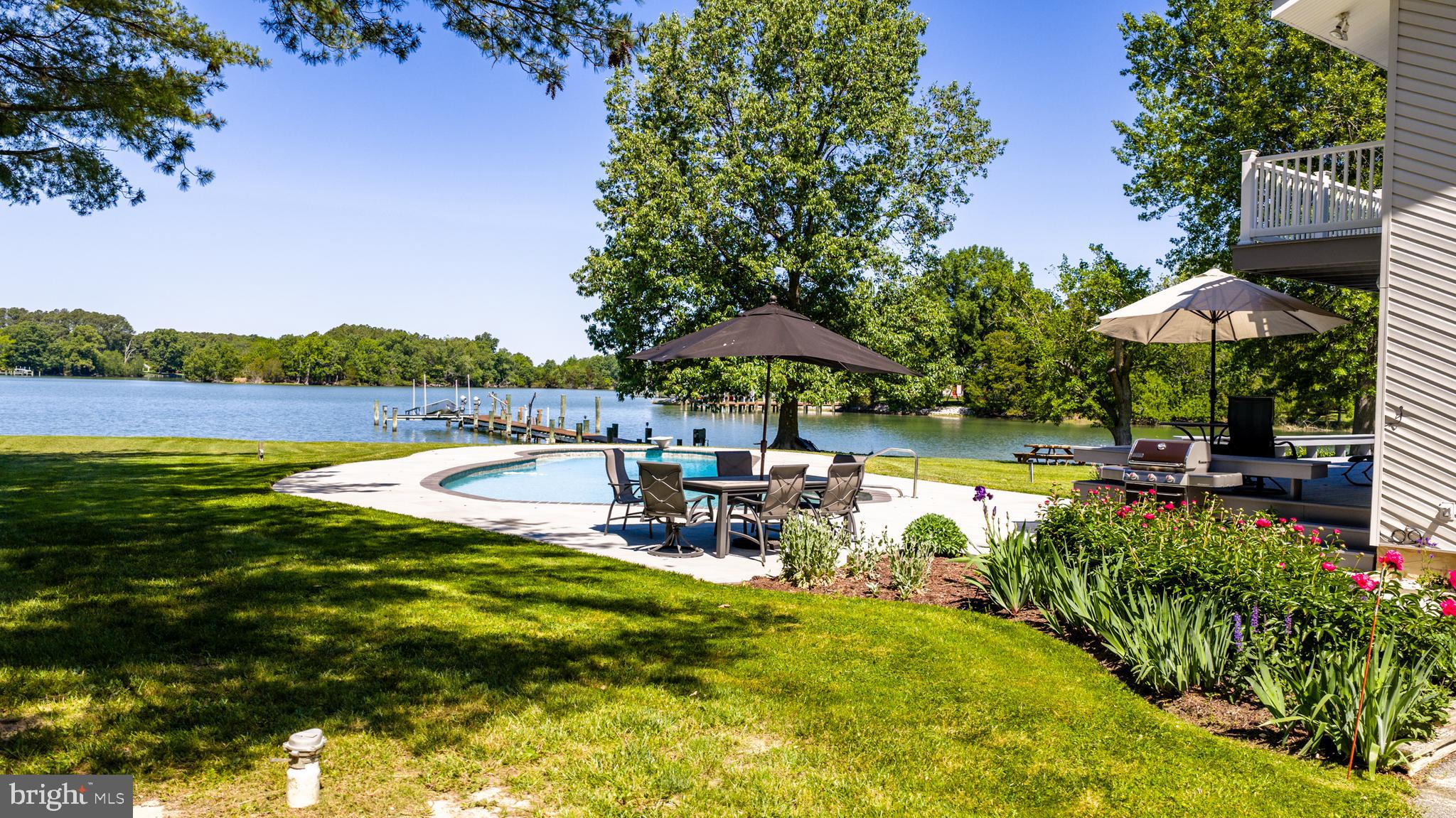 26282 Deep Water Harbor Road Easton, MD 21601 - Photo 35 of 53 a view of a swimming pool with a table and chairs under an umbrella