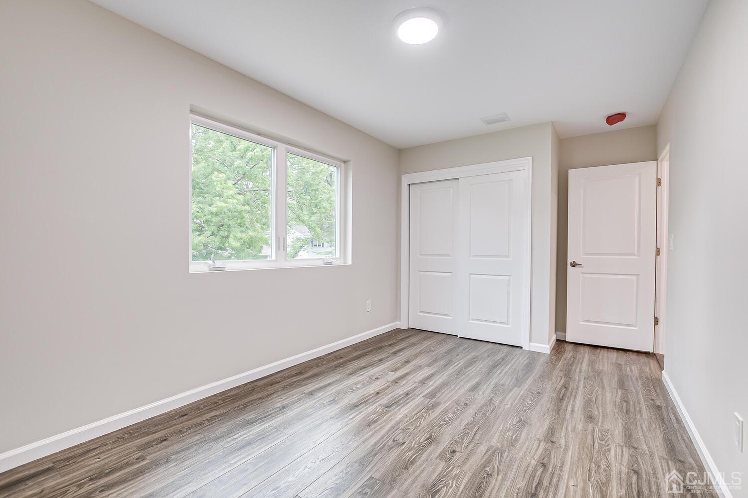 47 West Hill Road Colonia, NJ 07067 - Photo 10 of 18 an empty room with wooden floor and windows
