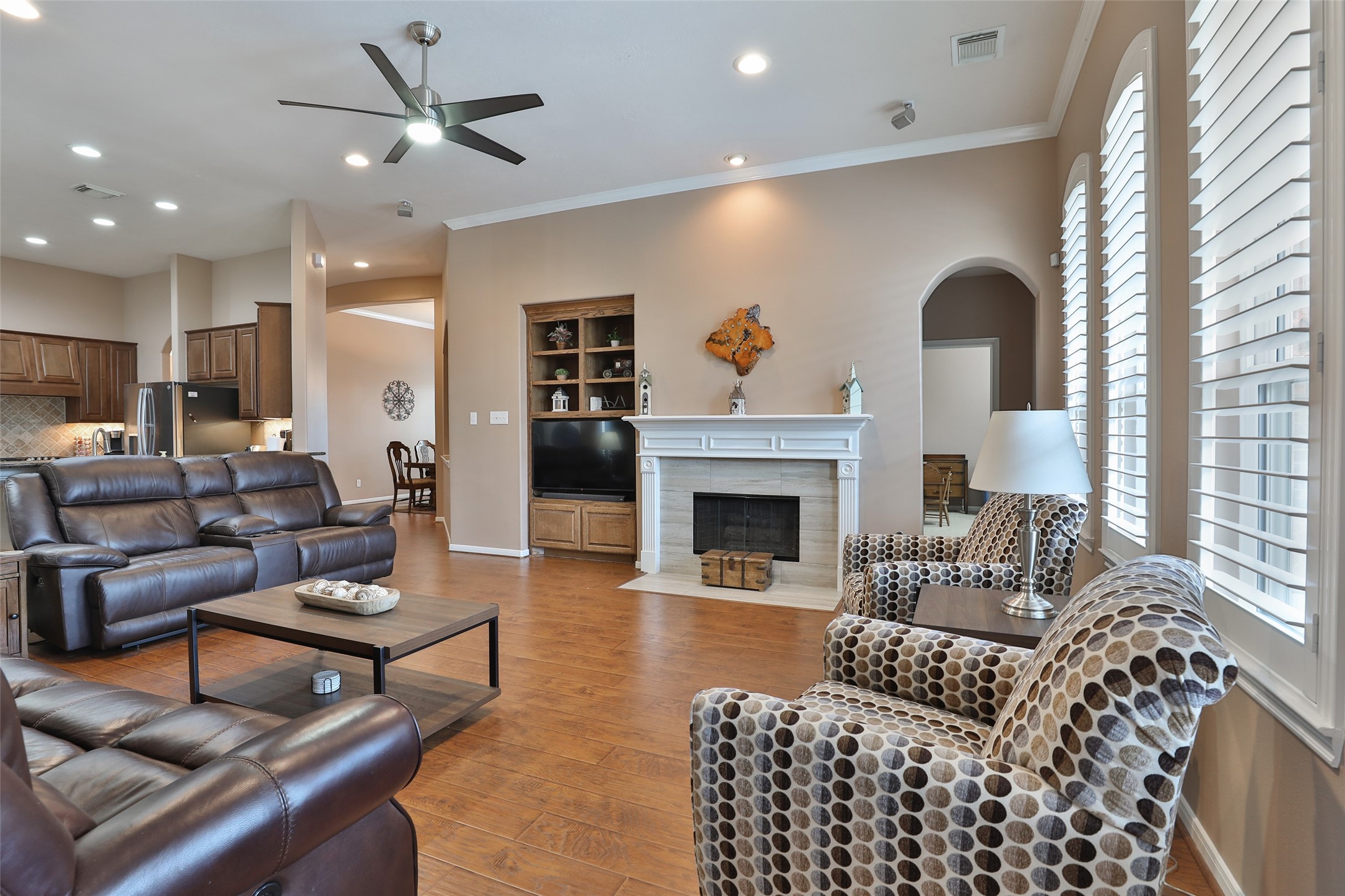 20519 Windrose Bend Drive Spring, TX 77379 - Photo 18 of 37 This spacious living area features a custom gaslog fireplace accented by upgraded tile, elegant crown molding, integrated surround sound, and built-in cabinetry. Plantation shutters offer adjustable privacy while beautifully framing views of the backyard oasis.