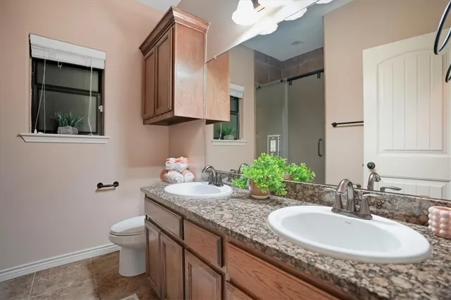 a bathroom with a granite countertop sink a toilet and mirror