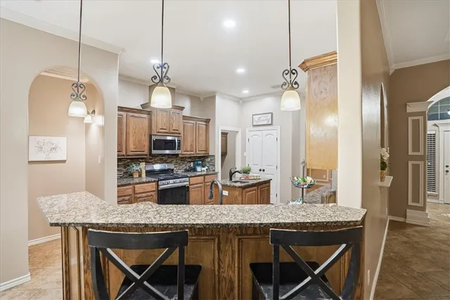 a kitchen with granite countertop a table chairs stainless steel appliances and cabinets
