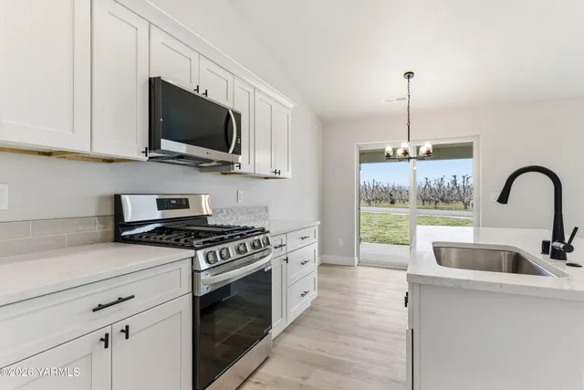 a kitchen with stainless steel appliances granite countertop a sink a stove and a wooden floors