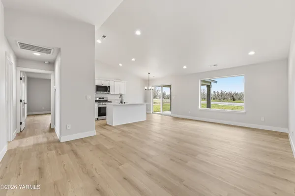 a view of an empty room with window and wooden floor